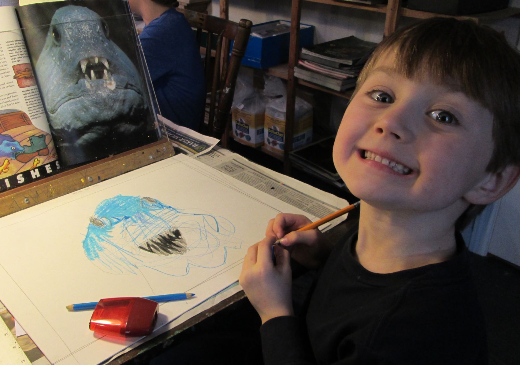 A delighted young student drawing a wolffish from a reference photo in the studio