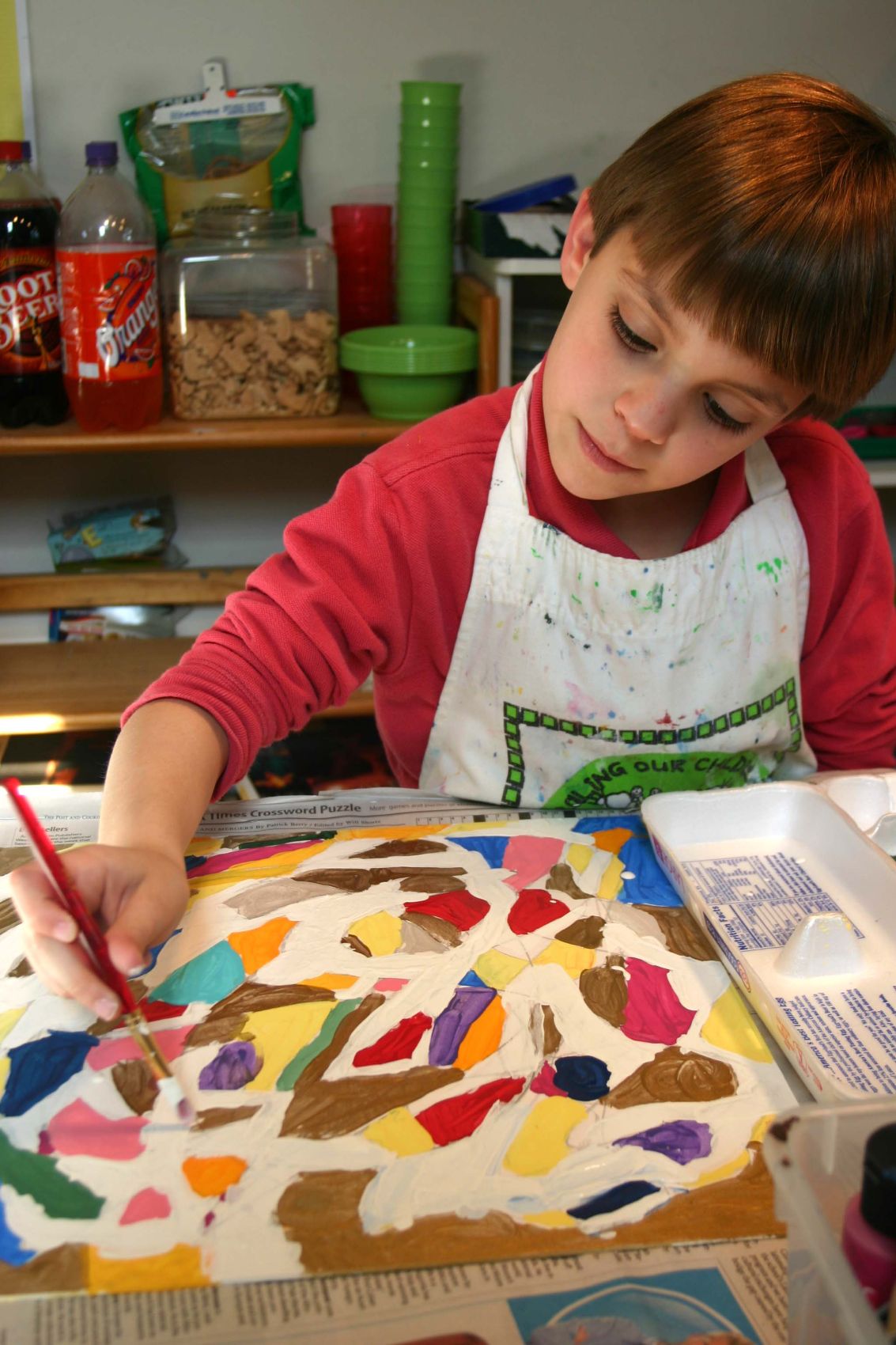 A focused young student filling a canvas with blocks of bright color in acrylic