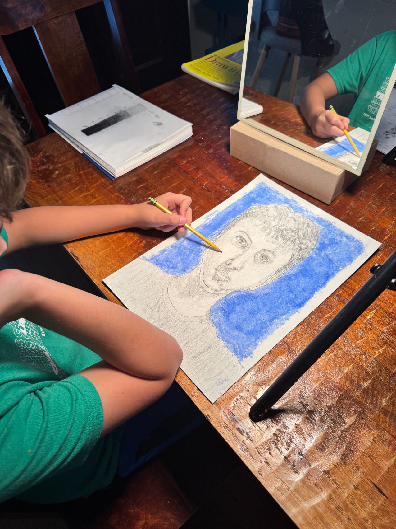 A young student drawing a self-portrait from a mirror in blue pastel