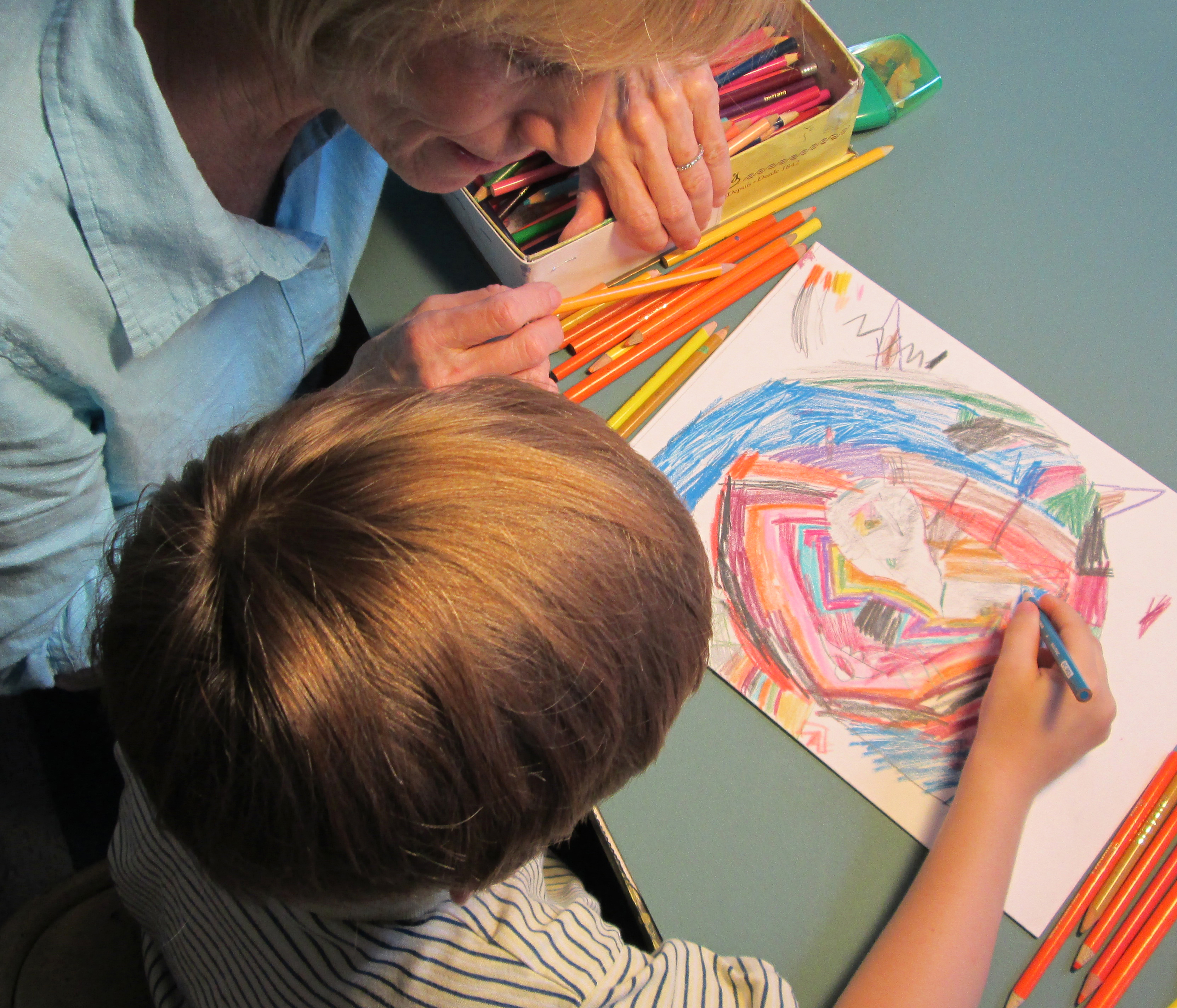 An art therapist and a young child drawing together with colored pencils during a session